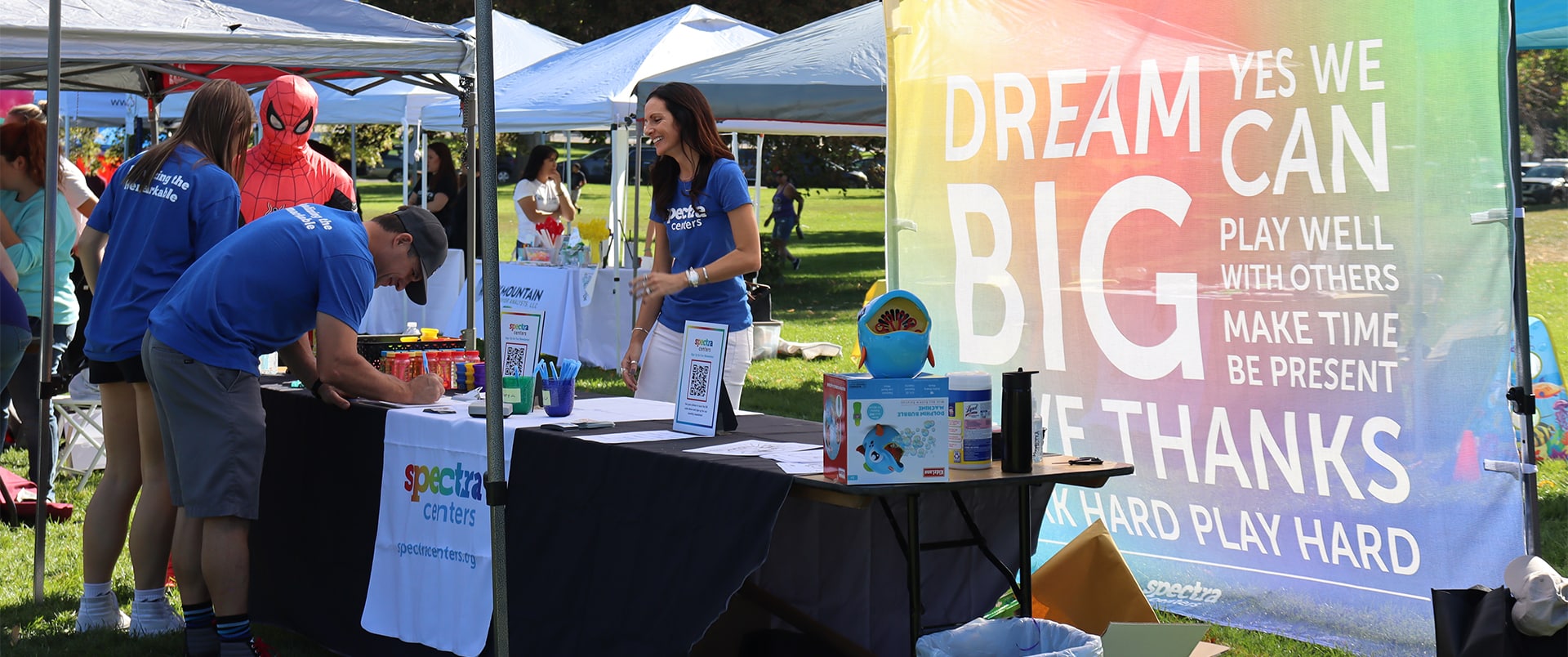 People signing paperwork at the Spectra Center booth at Walk for Autism